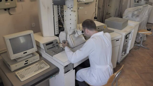 Old Style Laboratory. Female Scientist Looking Through Electronic Microscope
