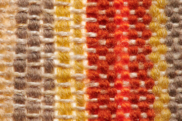 a small handmade rug or mat, woven from red and yellow wool threads, one object close-up
