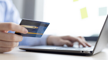 Woman's finger presses a keyboard and holds a credit card to register for payment or online transactions, Financial transactions and Internet security, Shopping online and banking online concept.