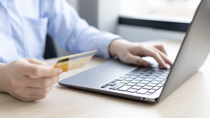 Woman's finger presses a keyboard and holds a credit card to register for payment or online transactions, Financial transactions and Internet security, Shopping online and banking online concept.