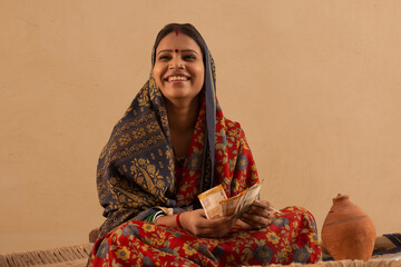 A RURAL WOMAN HAPPILY SITTING WITH MONEY IN HAND 