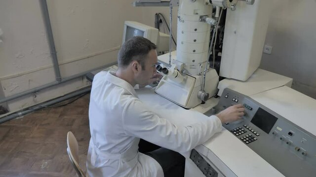 Research Scientist Looking Through Microscope In Laboratory 