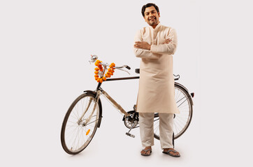 A RURAL MAN CONFIDENTLY POSING WHILE STANDING WITH NEW BICYCLE - obrazy, fototapety, plakaty