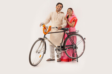 A HAPPY RURAL COUPLE STANDING TOGETHER AND POSING WITH NEW CYCLE