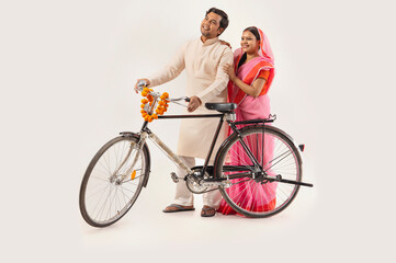 A RURAL COUPLE LOOKING AWAY WHILE STANDING WITH NEW BICYCLE