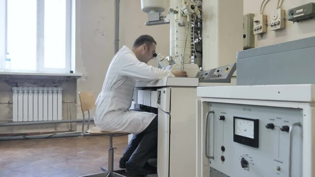 Research Scientist Looks Into Electronic Microscope In Laboratory