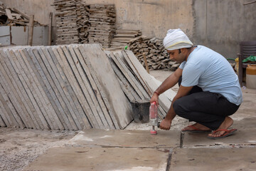 A LABOURER WORKING ON TILE WITH ELECTRIC EQUIPMENT