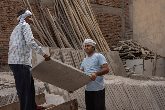 A LABOURER PASSING BLOCK OF TILE TO ANOTHER LABOURER
