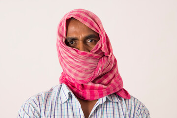 A LABOURER WITH HIS FACE COVERED WITH CLOTH LOOKING AT CAMERA 