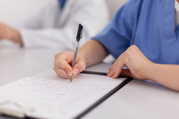 Close-up of physician woman nurse hand analyzing sickness examination writing medical expertise on clipboard prescribing pill medication treatment. Specialist teamwork working in meeting room