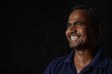 A LABOURER HAPPILY LAUGHING WHILE LOOKING AWAY
