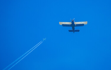 Two types of aircraft in the sky. The plane flies over the fields, spraying the fields with insecticides for a good harvest.