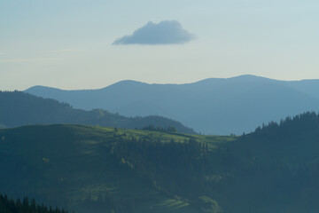 mountains in haze at sunrise with one cloud, background