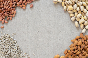 Different nuts lie on a gray background: seeds, pistachios, peanuts and almonds