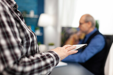 Close up of senior woman hand scrolling on digital device in home. Close up of elderly woman using...