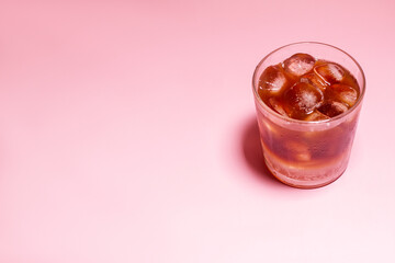 Iced coffee in a glass on pink background. Cold refreshment summer drink