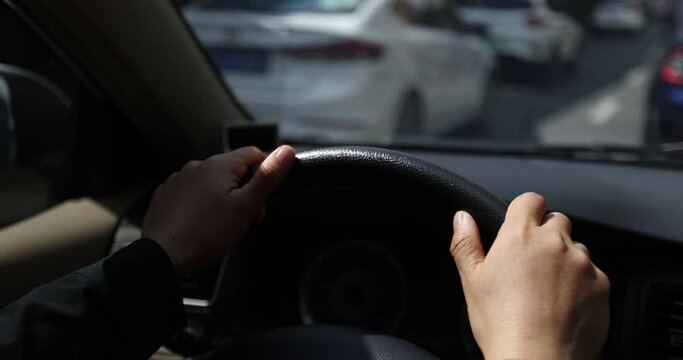 Driving car on city road, hands holding the steering wheel. 