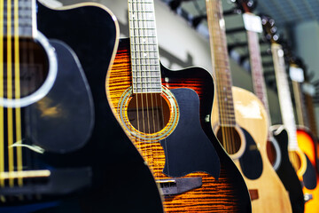 Naklejka premium Wooden guitars in a shop window. Wholesale and retail trade in musical instruments. Close-up. Selective focus
