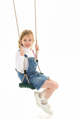 Happy little girl schoolgirl swinging on a swing.