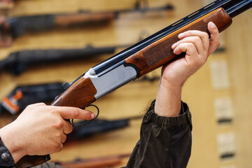 Choosing a hunting rifle in the store. A man tests firearms for accuracy. Unrecognizable person