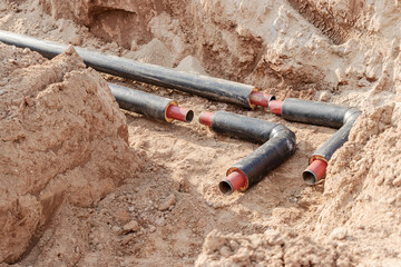 Laying heating pipes in a trench at construction site. Energy efficient insulated pipes. Cold and...