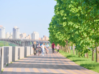 Fototapeta premium Blurred unfocused city view at day time. Unfocused people in the embankment.