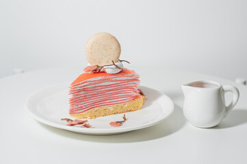 Strawberry crepe cake with macaroon on a plate on a white colour wooden plate.food desert concept.