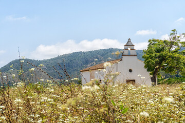 Landscape with a small church with white walls, with a mountainous and natural background.