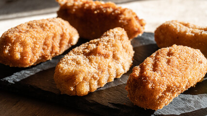 Homemade croquettes, on a black slate plate, and in direct sunlight.