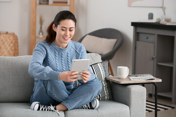 Obraz premium Young woman using tablet computer at home