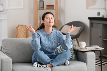 Young woman meditating at home - obrazy, fototapety, plakaty