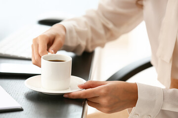 Young woman with cup of coffee in office, closeup