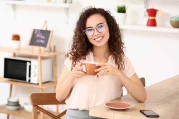 Beautiful young woman drinking coffee in kitchen