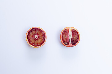 Conceptual flat lay of a blood orang, cut in half differently on a white copy space background, top...