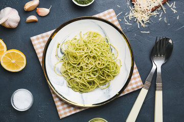 Plate with tasty pesto pasta on dark background