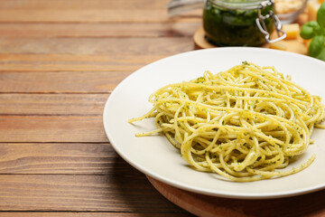Plate with tasty pesto pasta on table
