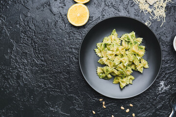 Plate with tasty pesto pasta on dark background