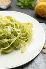 Plate with tasty pesto pasta on table, closeup