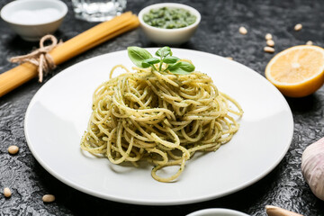 Plate with tasty pesto pasta on dark background