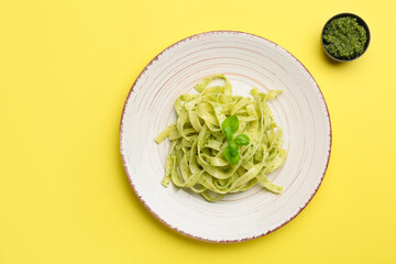 Plate with tasty pesto pasta on color background