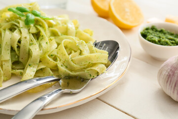 Plate with tasty pesto pasta on table