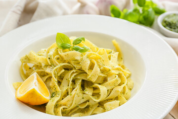 Plate with tasty pesto pasta on table, closeup