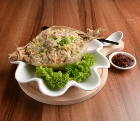 traditional chinese stir egg fried rice with seafood and meat wrapped in leaf on wood table asian halal menu