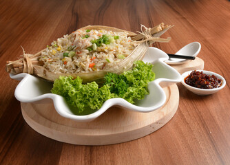 traditional chinese stir egg fried rice with seafood and meat wrapped in leaf on wood table asian halal menu