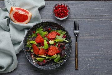 Plate with tasty grapefruit salad on dark wooden background