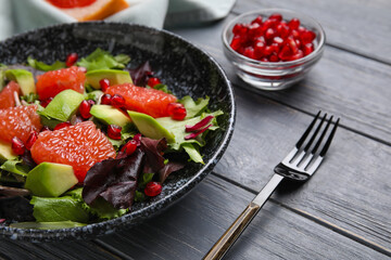 Plate with tasty grapefruit salad on dark wooden background