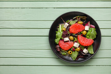 Plate with tasty grapefruit salad on color wooden background