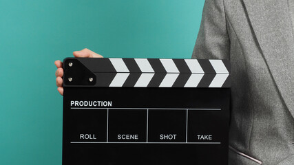 Woman hands holding black Clapperboard or film slate and wear grey suit. it use in videography...