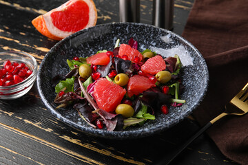 Plate with tasty grapefruit salad on dark wooden background