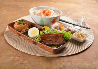 double boiled pumpkin rice congee porridge with braised pork belly , egg, fried bean curd tofu and peanut sour vegetable bento set on wood table asian halal menu